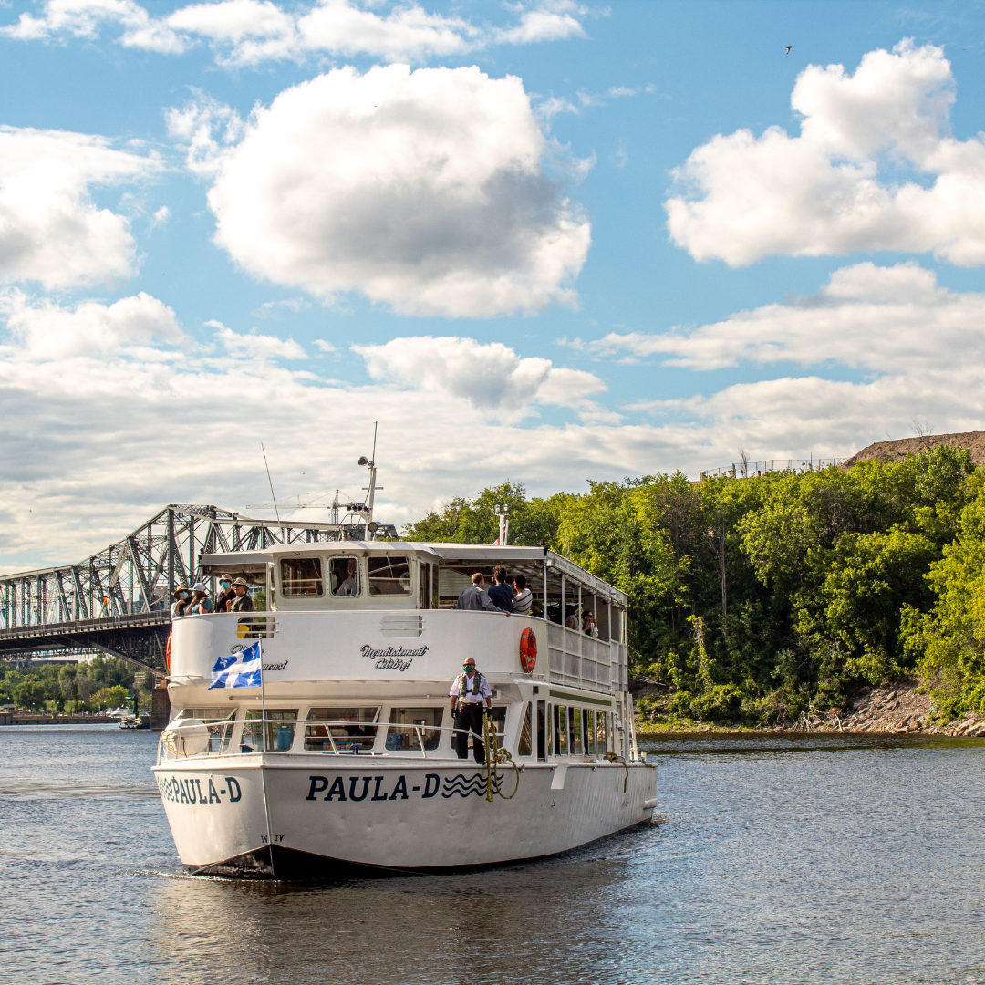 Father's Day Brunch Cruise boat Paula-D cruising on the river with a bridge in the background on a sunny day.