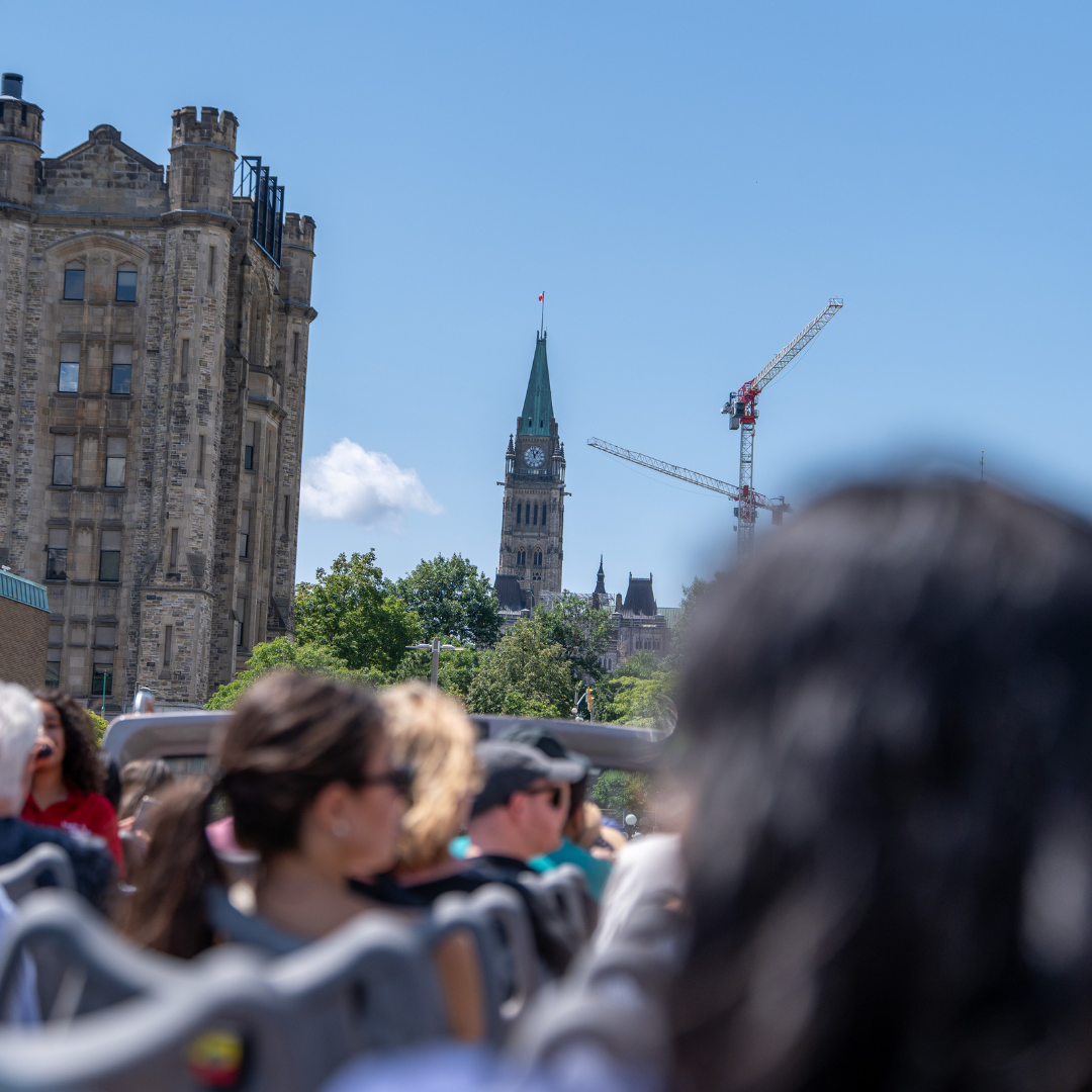 Ottawa Classic City Sightseeing Tour passengers enjoying views of the iconic Parliament Hill on an open-top bus.