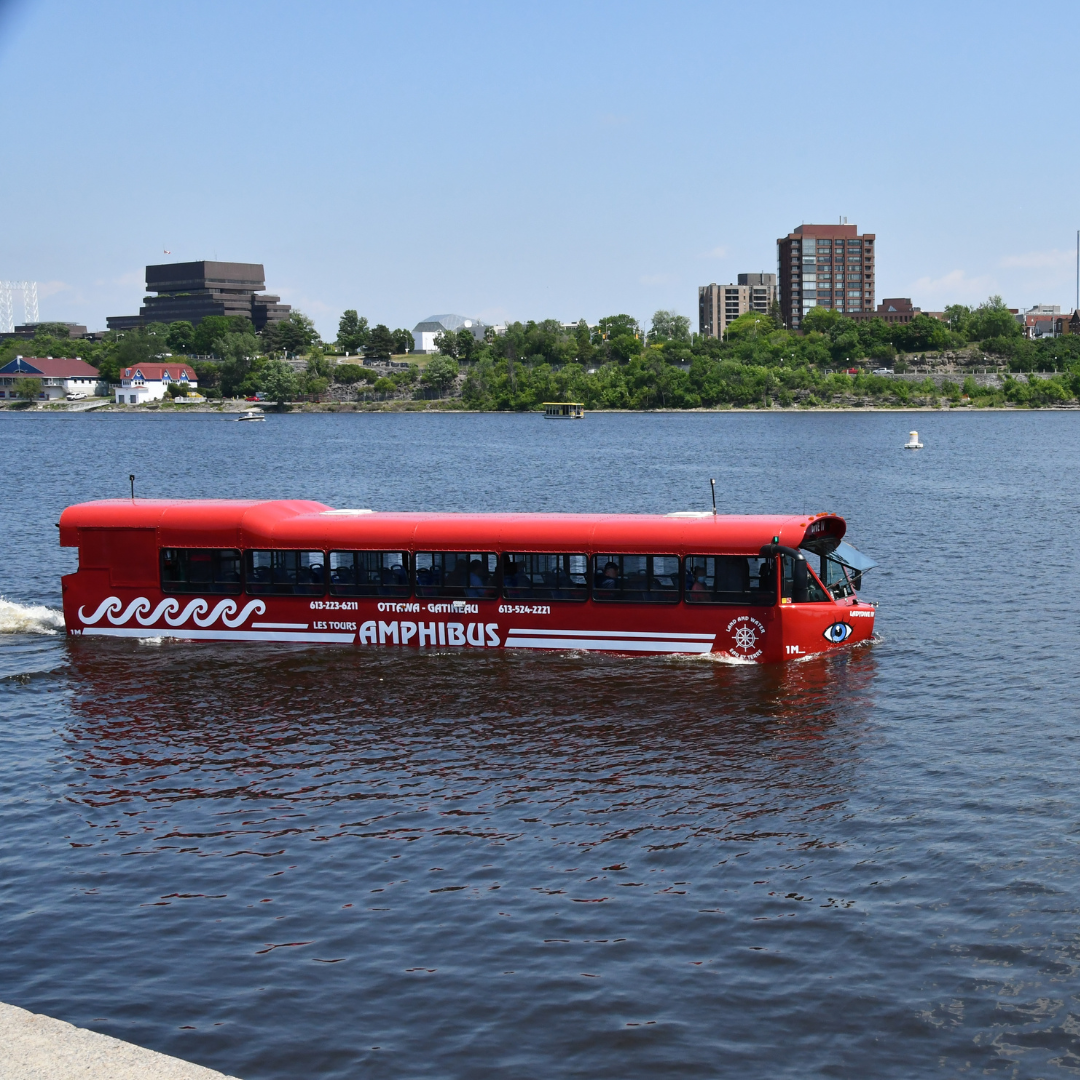 Ottawa Amphibious Boat Tour: The Lady Dive Amphibus tour cruising smoothly on the Ottawa River with a panoramic view of the Ottawa city skyline in the background.